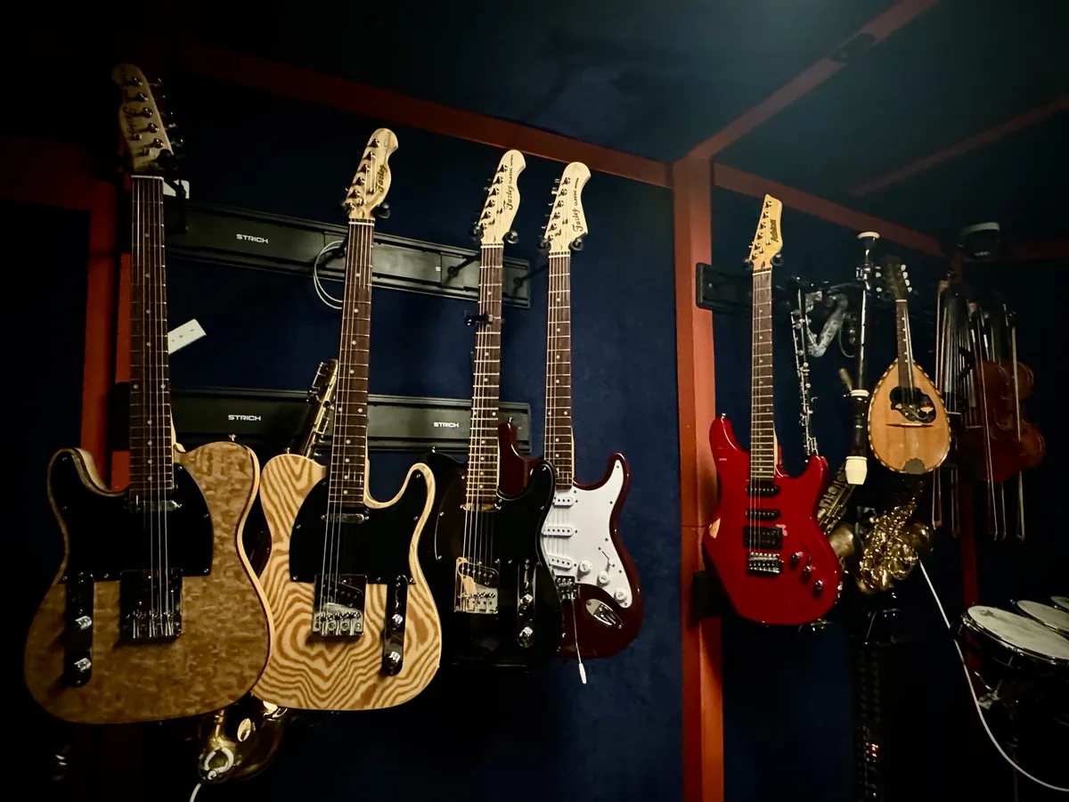 Electric guitars, basses and a mandolin hanging on the live room wall at 4chordsStudios